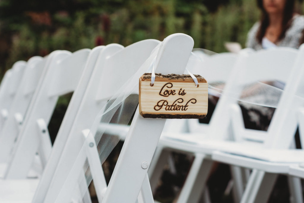 love is patient sign hanging on a chair at an outdoor wedding at the Hanna Garden