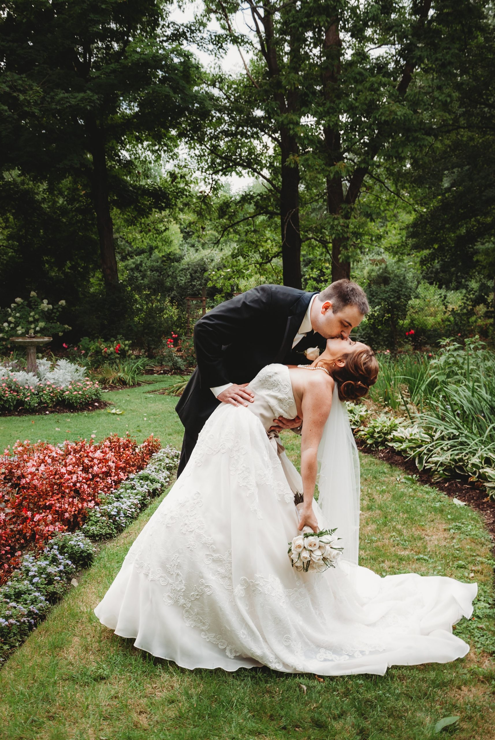 newlyweds kiss in the gardens of Mooreland Mansion in Kirtland Ohio