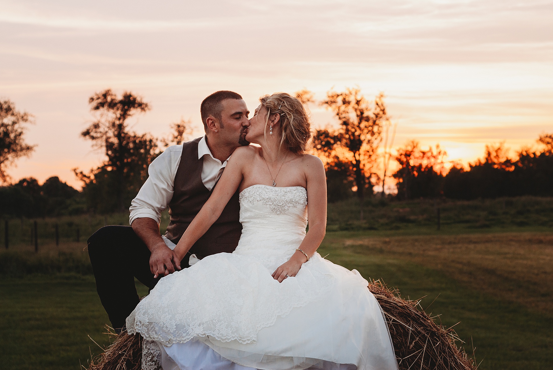 bride and groom kiss with sunset in the background 