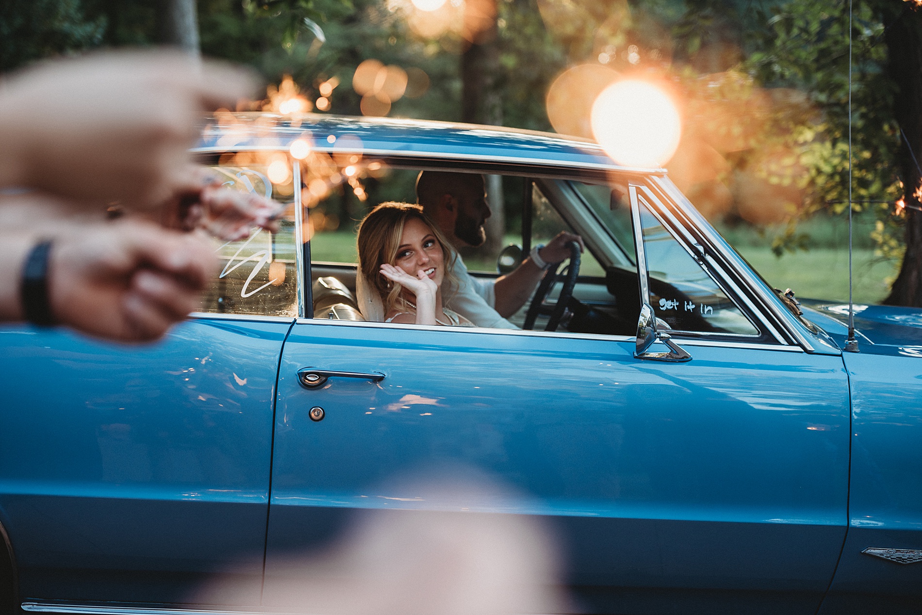 bride waves from car as newlyweds drive away from The Gish Barn an Ohio wedding venue