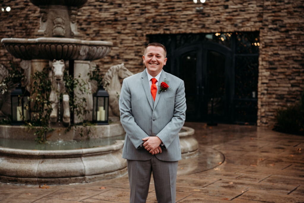 groom smiling near a fountain