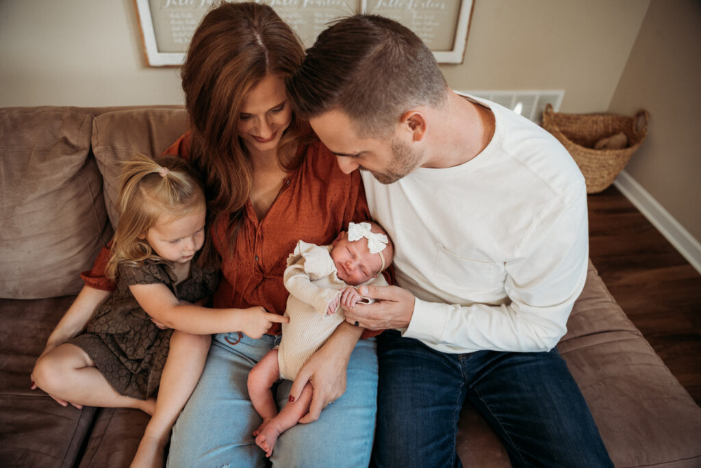 new family of four looking at their newborn girl