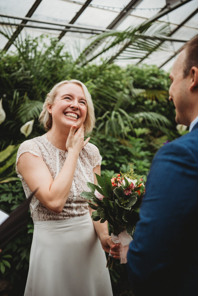 bride laughing with greenery behind her
